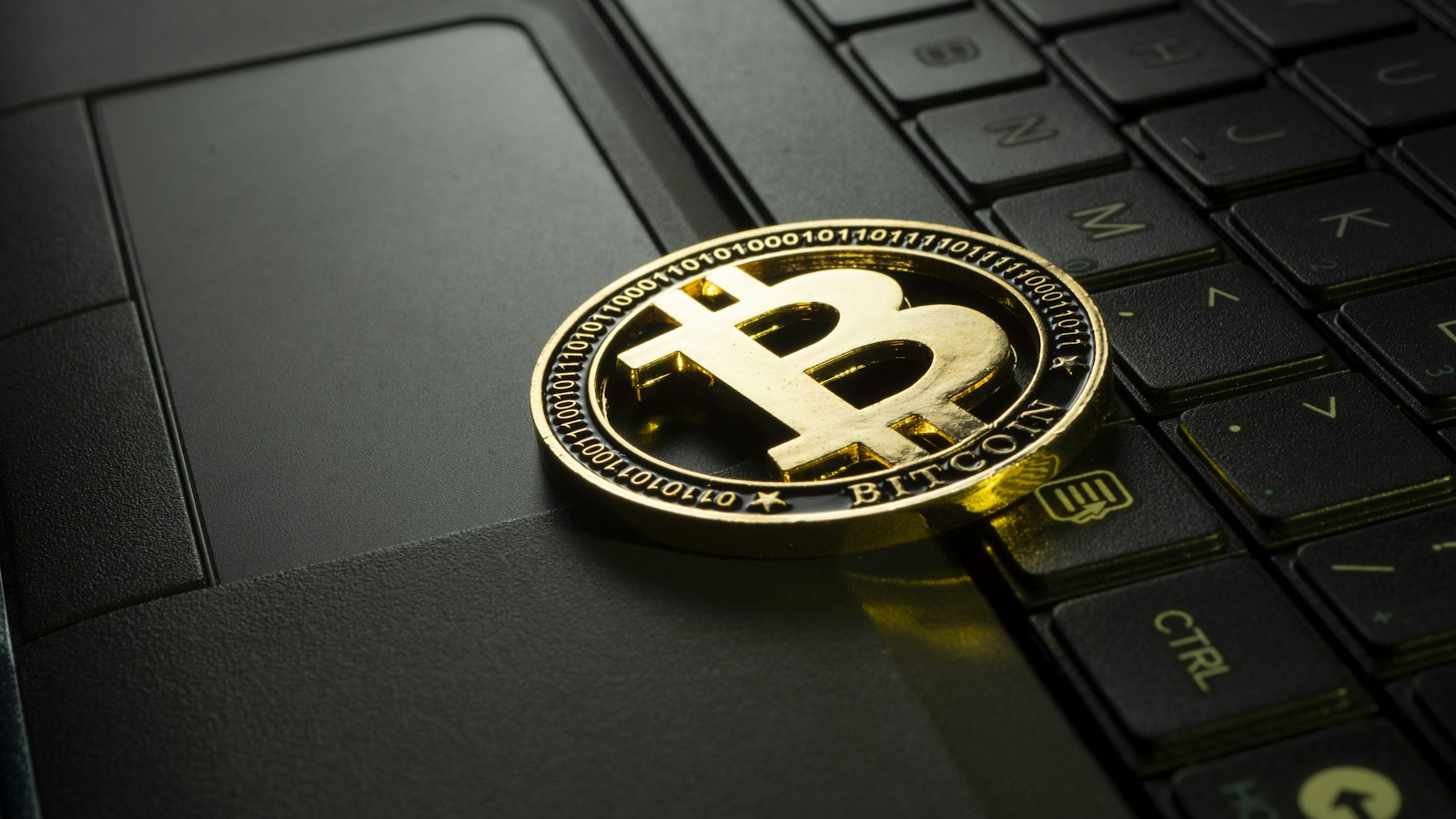 Physical Bitcoin coin resting on a laptop keyboard
